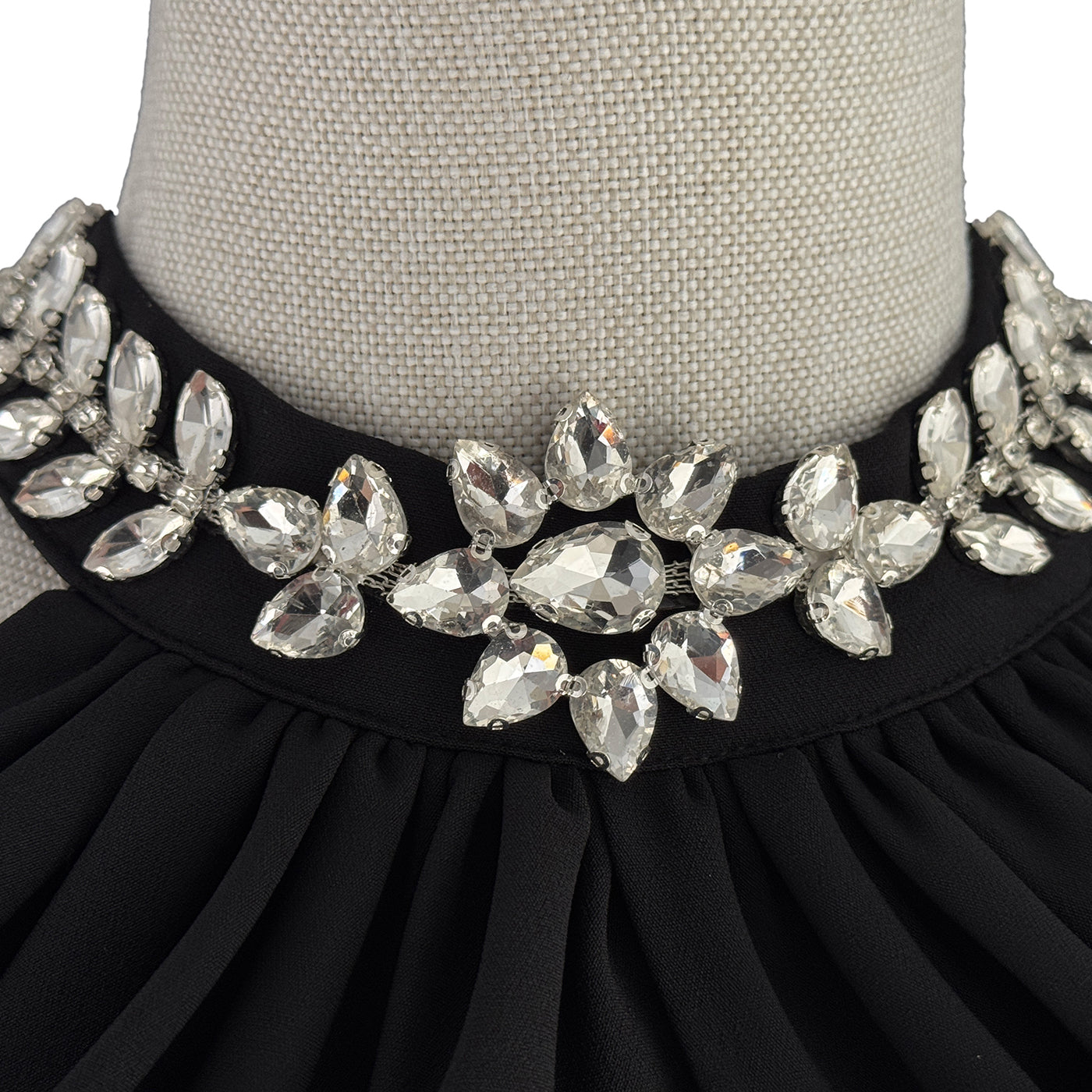 Black dress with a decorative crystal collar on a mannequin.